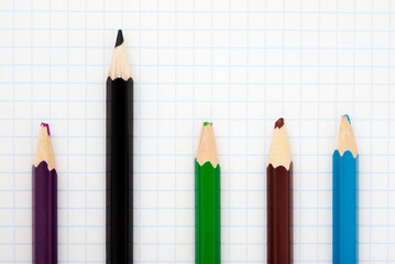  sharp black pencil and four colored blunt pencils on the squared paper sheet