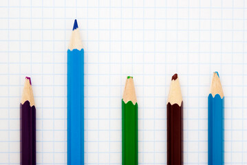 sharp blue pencil among blunt colored pencils on a writing-book leaf