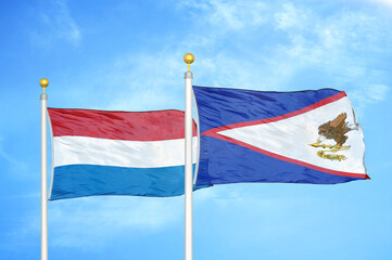 Netherlands and American Samoa two flags on flagpoles and blue sky