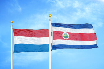 Fototapeta na wymiar Netherlands and Costa Rica two flags on flagpoles and blue sky