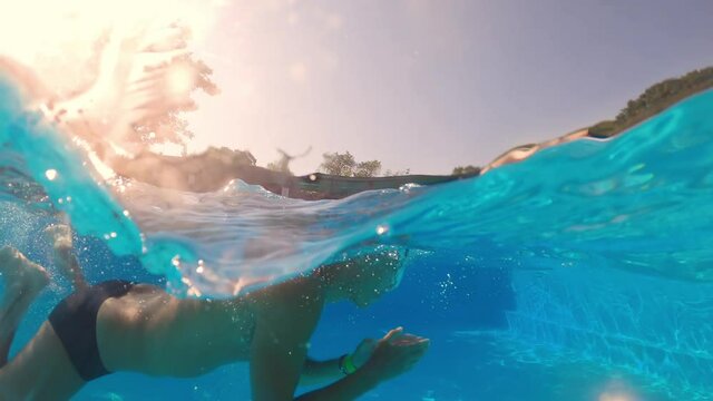 Underwater shooting. Man dive in blue swimming pool.