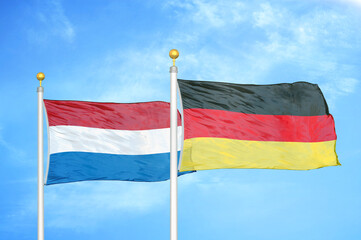 Netherlands and Germany two flags on flagpoles and blue sky