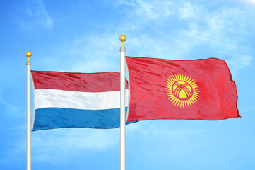 Netherlands and Kyrgyzstan two flags on flagpoles and blue sky
