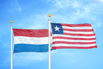 Netherlands and Liberia two flags on flagpoles and blue sky