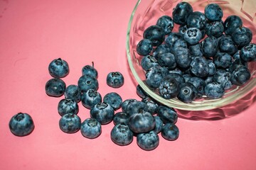 blueberries in a glass bowl  on a pink background