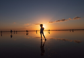Beautiful sunset on the lake, the sun reflecting in the water, silhouette of a girl in the middle