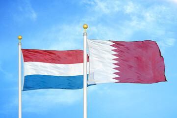 Netherlands and Qatar two flags on flagpoles and blue sky