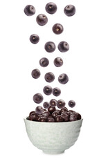 Fresh acai berries falling into bowl on white background