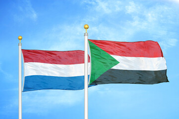 Netherlands and Sudan two flags on flagpoles and blue sky