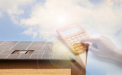 Double exposure of house with installed solar panels and woman using calculator. Renewable energy...