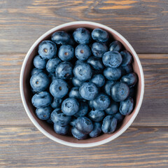 Fresh juicy blueberries on a plate. Wooden background