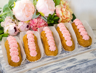 Yummy vanilla eclairs on wood with flower decoration