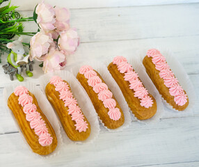 Yummy vanilla eclairs on wood with flower decoration