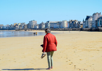 Brittany, France: A 76 year old person walks on the beach of Saint Malo in a peaceful moment and alone contemplates the ocean.