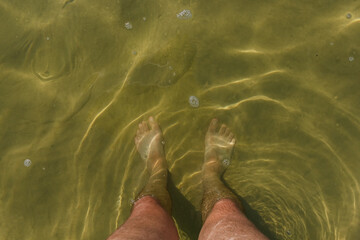 Male feet in the water of the lake