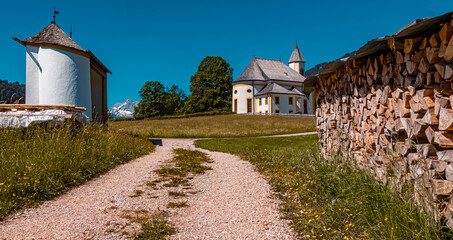 Beautiful alpine view with a stack of wood near the famous Mariä Heimsuchung sanctuary, Ettenberg,...