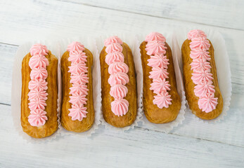 Yummy vanilla eclairs on wood with flower decoration