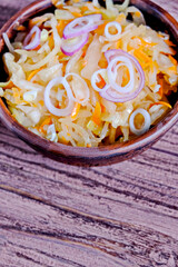SauPickled cabbage in bowl with wooden spoon and seasoning.  Vegetarian clean food. Paleo diet. Healthy eating concept . With carrot in a plate. Top view. Copy space.