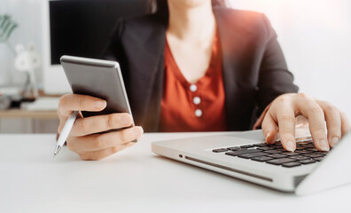 Fototapeta premium businesswoman hand using smart phone,mobile p payments online shopping,omni channel,digital tablet docking keyboard computer at office in sun light