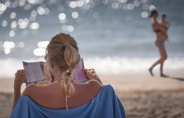 signora con giornale al mare