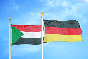 Sudan and Germany two flags on flagpoles and blue sky