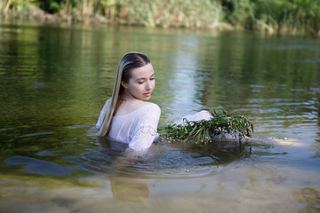 Young white woman with long blondy hair in a river in a forest in summer