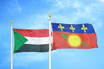 Sudan and Guadeloupe two flags on flagpoles and blue sky