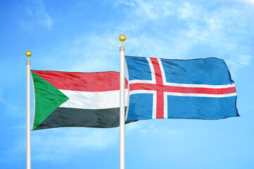 Sudan and Iceland two flags on flagpoles and blue sky