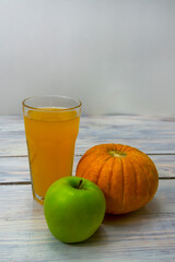 Glass of homemade pumpkin apple juice close-up. Pumpkin and apple on wooden background. Healthy food concept. Selective focus, copy space
