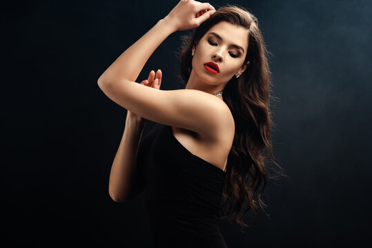 beautiful woman in black dress with red lips on black background