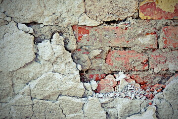 Vintage brick rough rustic wall with cracked plaster.Texture of old brick wall with peeling plaster. Beautiful background of old brickwork of the historic building.