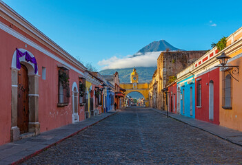 Cityscape of Antigua city at sunrise with Santa Catalina arch and Agua volcano, Guatemala.