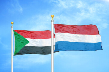 Sudan and Netherlands two flags on flagpoles and blue sky