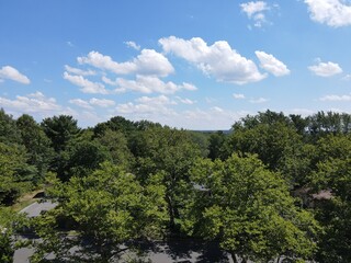 Panoramic aerial view of a section of Old Bridge township from above the tree tops with some cumulus clouds in the horizon