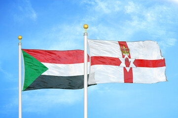 Sudan and Northern Ireland two flags on flagpoles and blue sky