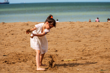 Happy child playing with sand at the beach in summer, Botany Bay, Kent, UK