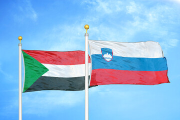 Sudan and Slovenia two flags on flagpoles and blue sky