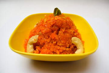 Selective focus of Gajar ka Halwa, a popular Indian, Pakistani sweet dish dessert, made of grated carrot. Garnished iwth cashewnuts, pista, dry fruits in a yellow bowl ready to serve hot or cold