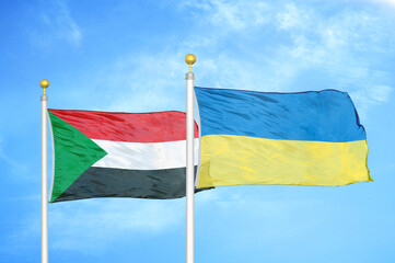 Sudan and Ukraine two flags on flagpoles and blue sky
