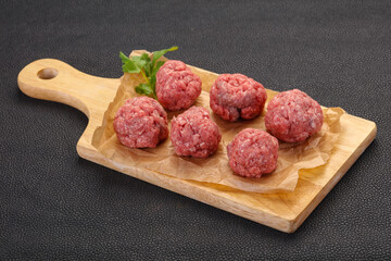 Raw meatball over wooden background
