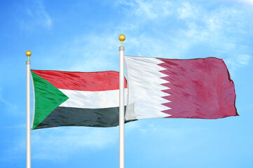 Sudan and Qatar two flags on flagpoles and blue sky