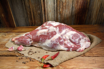 A raw leg of mutton on a bone lies on a wooden table. Sheep meat close-up.A fresh piece of mutton....