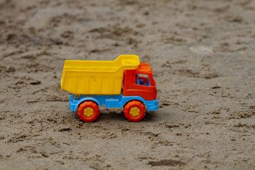 Colorful toy truck on the sand outdoors. Horizontal shot. Copy space