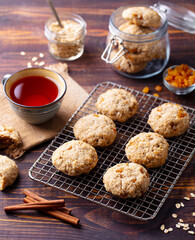 Oat vegan cookies on cooling rack with cup of tea. Wooden background.