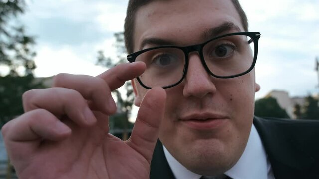 funny guy nerd in suit and glasses tells something to the camera very enthusiastically. Typical nerdy close-up face tells story.