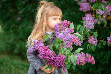 Fototapeta premium little girl in a coat near lilac