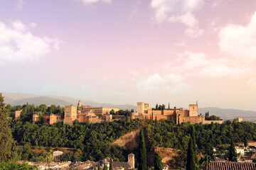 colorful landscape of Granada city at sunset, with the Alhambra in the background, mountains, trees and the sky with clouds for a nice postcard or wallpaper