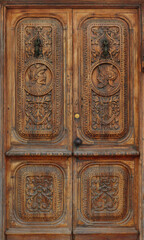 Fototapeta na wymiar ancient and worn wooden gate with engraved ornaments in the wood