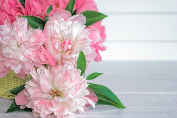 a bouquet of pink peonies on the table and in a wicker basket close-up. background with bright pink peonies.