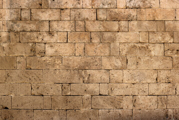 brickstones of and ancient wall of a medieval castle or a fortress - surface of yellow stone bricks texture background	